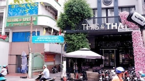 A street view with a coffee and tea house named 'THIS & THAT' and a restaurant 'NHA HANG TULPRESENT'. - WE stayin Saigon Ben Thanh Market City View Studio (Ho Chi Minh City)