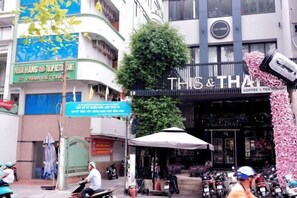 Une vue d’une rue avec un café-salon de thé appelé « THIS & THAT » et un restaurant appelé « NHA HANG TULPRESENT ».