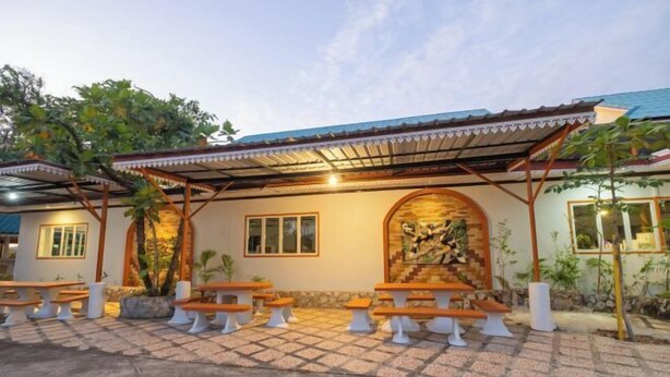 An outdoor seating area with wooden benches and a covered patio. - Sleepdive Samaesan (Sattahip)