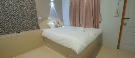 Quarto com cama, janela com cortinas, porta e luminária fixada na parede.