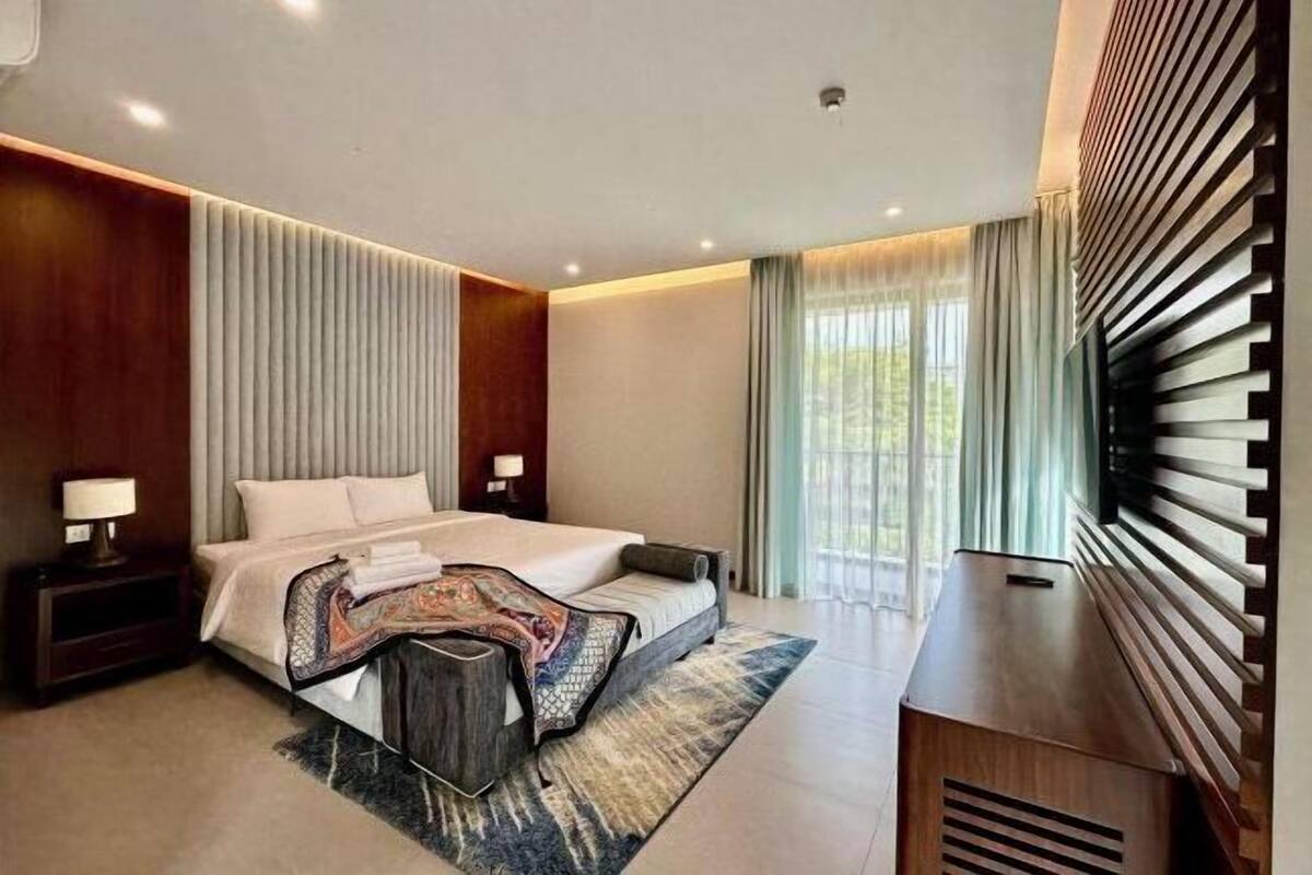 A modern hotel room with a large bed, a desk, and a view of the outdoors.