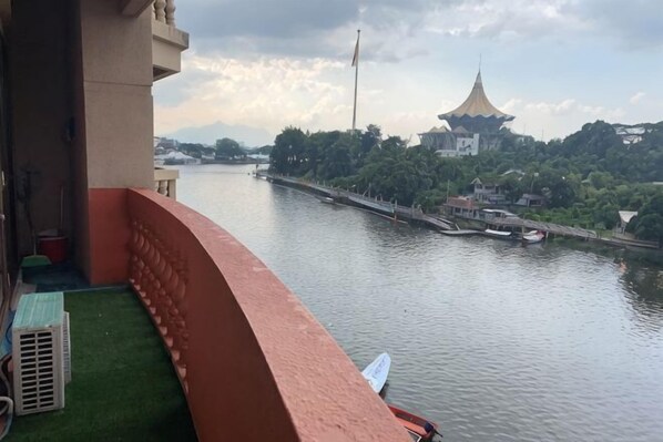 Un balcón con vista a un río, un edificio tradicional y un puente.