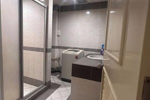 Un baño con mampara de vidrio, inodoro y lavamanos.
