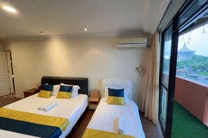 Habitación de hotel con dos camas, vista a un edificio a través de una ventana y un equipo de aire acondicionado en la pared.