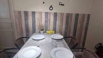A dining table set for four with chairs, a vase with flowers, and a wall with a striped pattern.