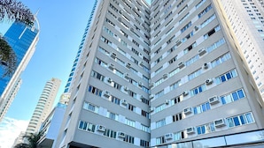 A multi-story building with a modern architectural design, featuring a prominent corner entrance and a visible balcony on the ground floor. - Edificil Antares (Balneário Camboriú)