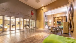 A spacious room with a wooden floor, a green cushion, a dining area with a table and chairs, and a mural on the wall. - Mulberry Verve Suites KL Mid Valley 4Pax 2 Bedroom (Kuala Lumpur)