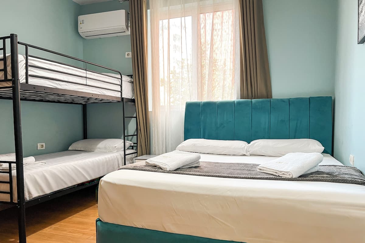 A room with bunk beds, a single bed, and a window with curtains.