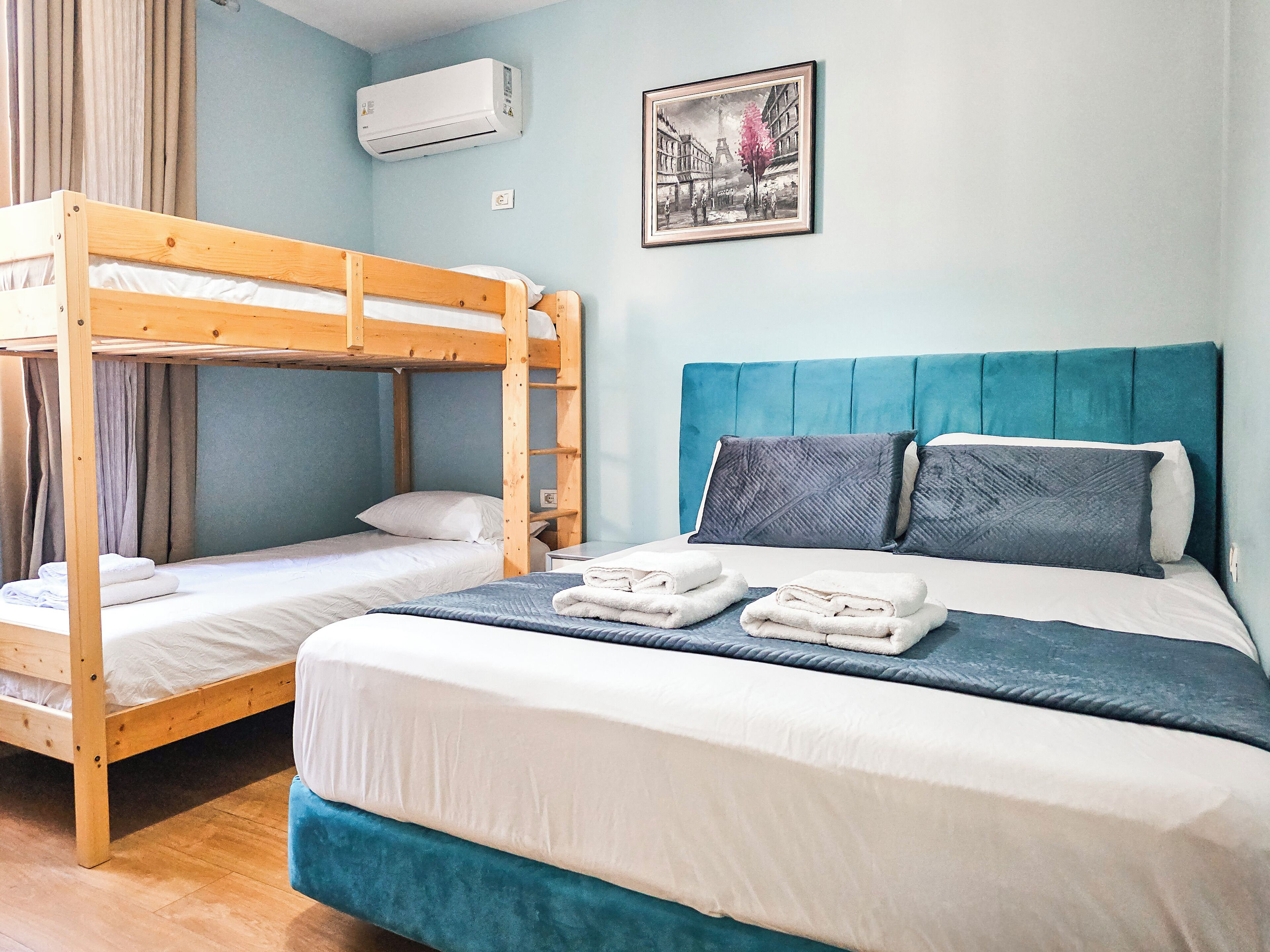 A room with a bunk bed, a single bed, and a framed picture on the wall.