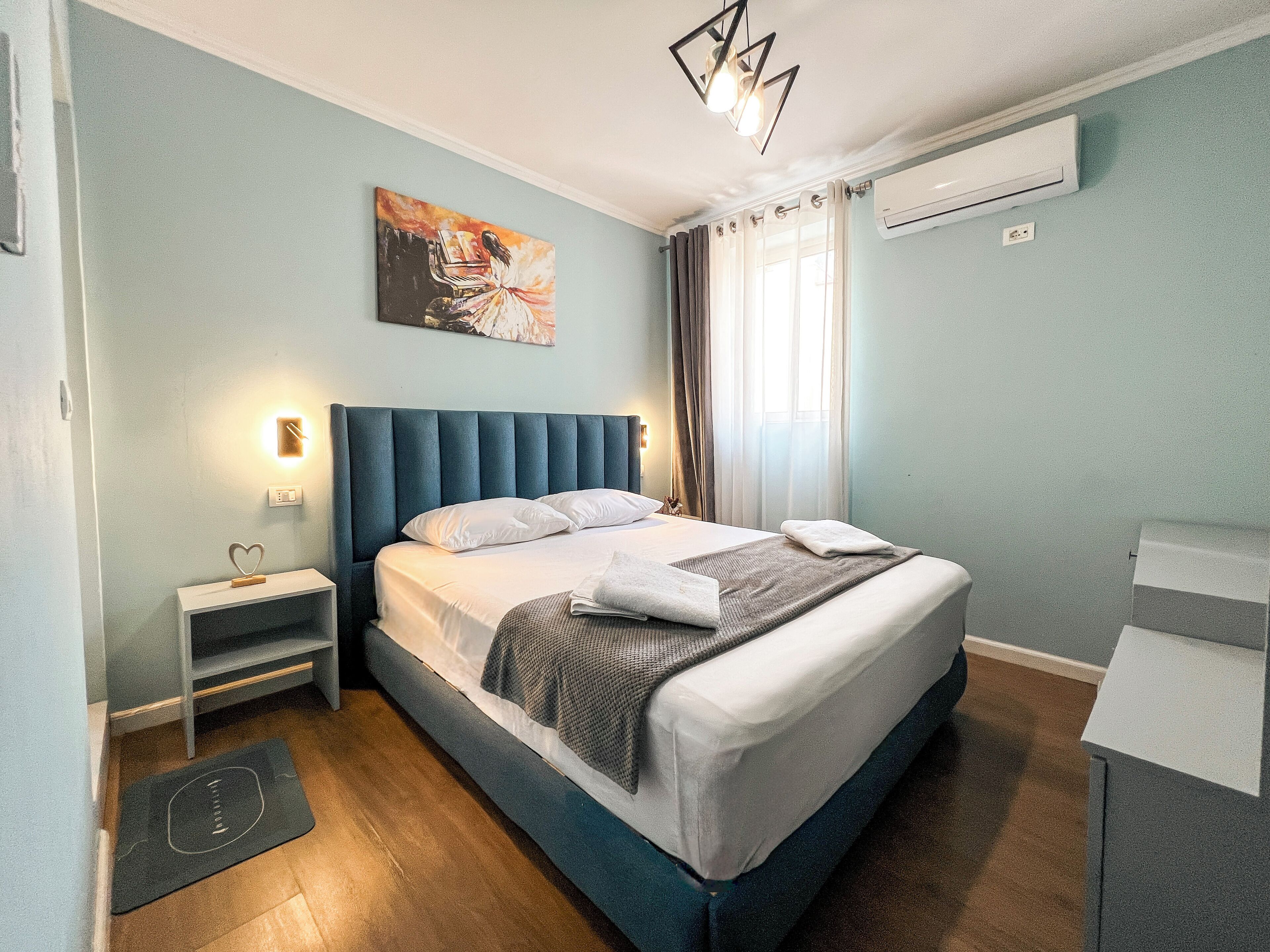 A neatly arranged bedroom with a bed, bedside table, and a painting on the wall.