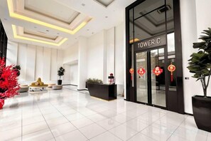 A hotel lobby with a reception desk, a large potted plant, and a modern ceiling design. - Legoland-7min walk at Happy Journey Stay @ Dpristine Lakeview(8pax) Max (Iskandar Puteri)