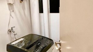 Une pièce avec un mur blanc, une porte dotée d’une poignée en laiton et un rideau blanc.