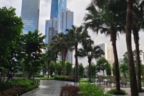 A pathway lined with palm trees and greenery, leading to a modern building complex with high-rise structures in the background. - Agile SkyView Suites KL (Kuala Lumpur)