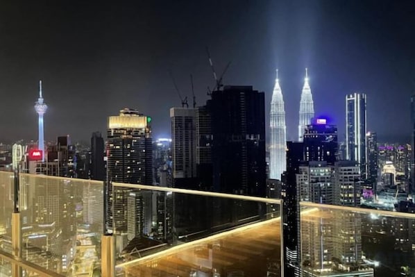 A nighttime cityscape with prominent skyscrapers, including the Petronas Towers, and a view of the skyline from a high vantage point. - Agile SkyView Suites KL (Kuala Lumpur)