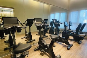 A gym with multiple exercise bikes and a laptop on each. - Agile SkyView Suites KL (Kuala Lumpur)