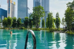 A swimming pool with a metal ladder, surrounded by greenery and tall buildings in the background. - Agile SkyView Suites KL (Kuala Lumpur)