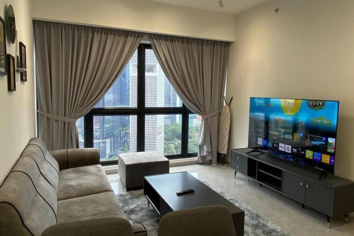 A modern living room with a large window, a sofa, a coffee table, and a flat-screen TV.