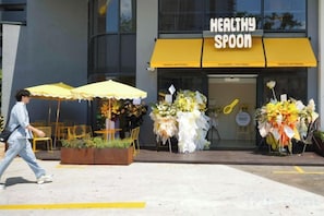 A storefront with a yellow awning labeled 'HEALTHY SPOON' and floral arrangements outside. - Agile SkyView Suites KL (Kuala Lumpur)
