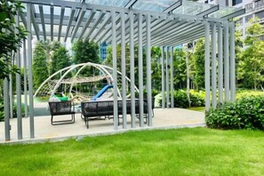 A covered outdoor seating area with a swing set and a slide. - Agile SkyView Suites KL (Kuala Lumpur)