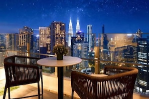 A balcony with a table and chairs, overlooking a cityscape at night. - Agile SkyView Suites KL (Kuala Lumpur)