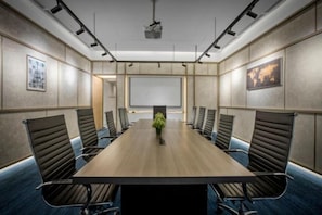 A conference room with a long table, chairs, a projector, and a screen. - Agile SkyView Suites KL (Kuala Lumpur)