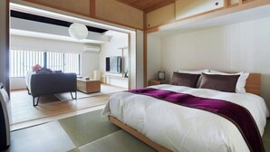 A modern bedroom with a bed, a sofa, a TV, and a window.