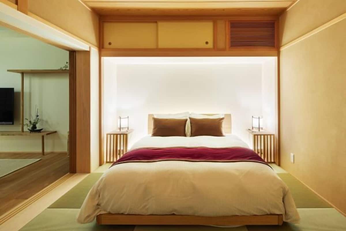 Un dormitorio con cama, mesitas de noche, televisión y vistas a una estructura de madera en el exterior.