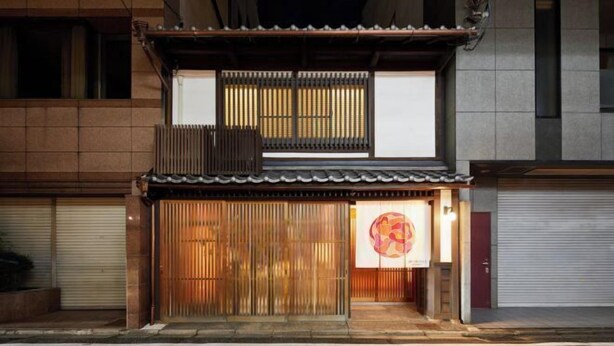 A traditional Japanese building with a wooden entrance and a sign with a colorful design.