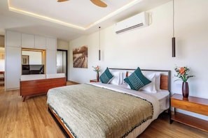 A bedroom with a bed, bedside table, and a mirror. - Oasis Residences Sanur – Family-Friendly 3-BR Villa with Private Pool & Garden (Bali)