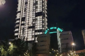 A multi-story hotel with illuminated signage indicating 'CAPS INTJ HOTEL' at night. - Meo's House - CSJ Seaside Apartment (Vung Tau)