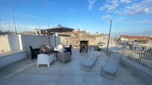 A rooftop terrace with outdoor seating, a piano, and a view of the cityscape. - Casa Bianca il Tuo Bnb, Big Terrace Downtown, 15Min Airport & Sea (Bitonto)