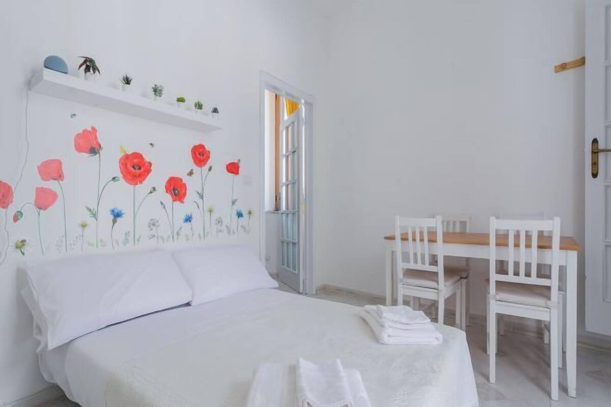 A bedroom with a bed, a desk, and chairs.