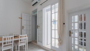 A room with a dining table and chairs, a large window with curtains, and a door with glass panels. - Casa Bianca il Tuo Bnb, Big Terrace Downtown, 15Min Airport & Sea (Bitonto)