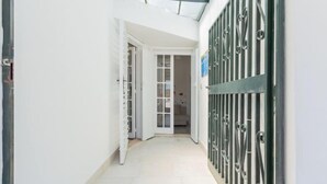 A narrow hallway with a tiled floor, a closed door on the left, and a metal gate on the right. - Casa Bianca il Tuo Bnb, Big Terrace Downtown, 15Min Airport & Sea (Bitonto)