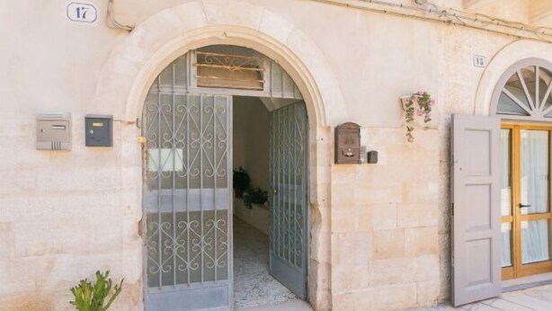 A stone building with a large arched entrance, a mailbox, and a potted plant. - Casa Bianca il Tuo Bnb, Big Terrace Downtown, 15Min Airport & Sea (Bitonto)