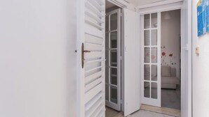 A white door with horizontal slats, a glass panel, and a brass handle. - Casa Bianca il Tuo Bnb, Big Terrace Downtown, 15Min Airport & Sea (Bitonto)