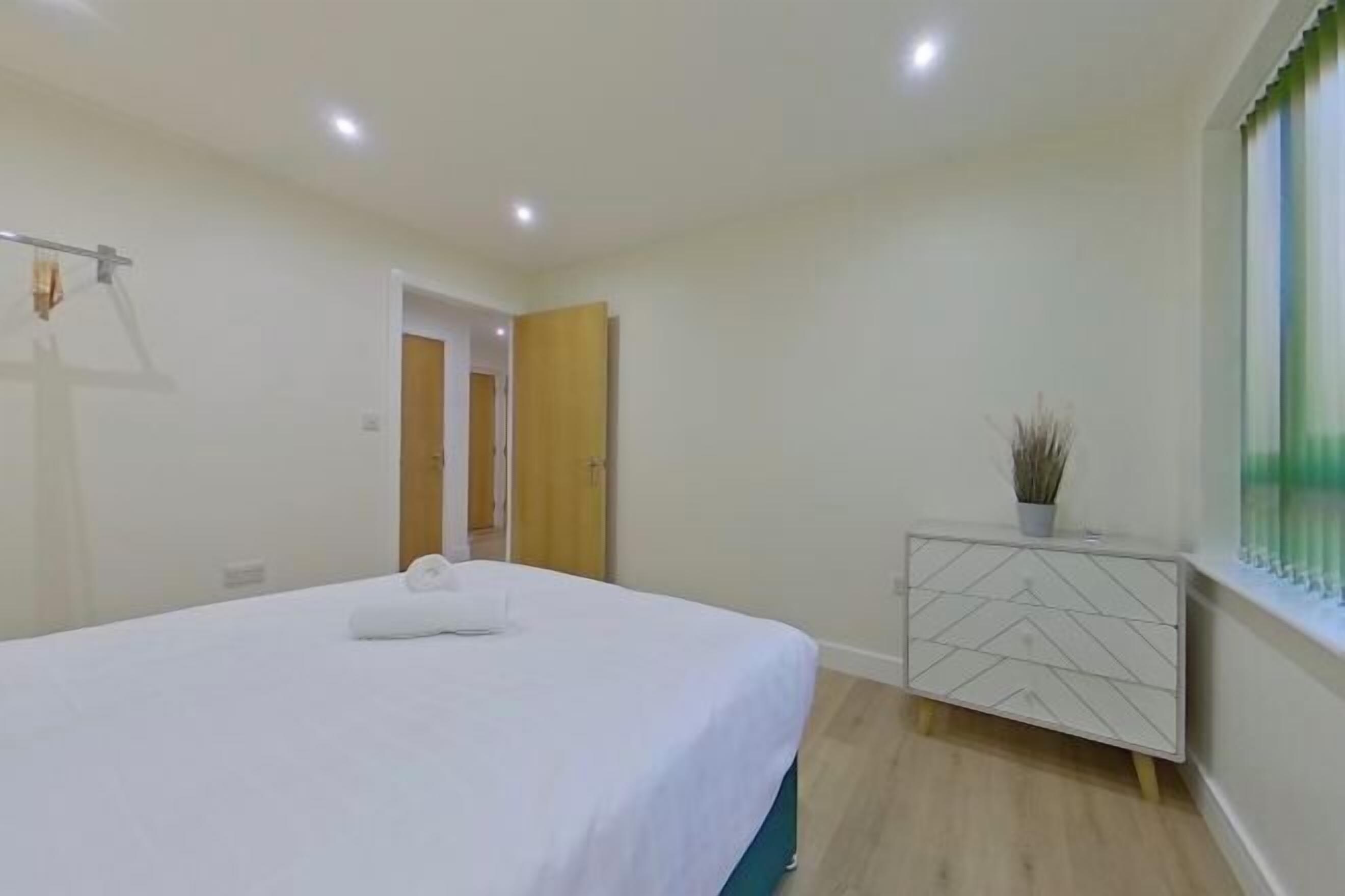 Una habitación de hotel con una cama, una mesita de noche con una planta y una ventana con persianas.
