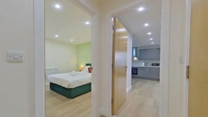 A modern bedroom with a bed, bedside table, and a small bedside lamp. - Beauchamp House - 2-Bed 2-Bath Apartment in Coventry City Centre by CovStays (Coventry)