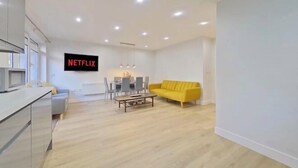 A modern living room with a yellow sofa, a dining area, and a kitchen area. - Beauchamp House - 2-Bed 2-Bath Apartment in Coventry City Centre by CovStays (Coventry)