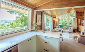 A cabin interior with a dining area, sofa, and a view of the outdoors.