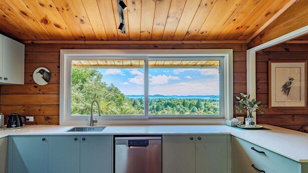 Una cocina con paredes de madera, un ventanal grande y un lavavajillas.