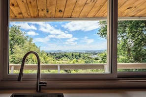 A window with a view of a green landscape and a clear sky.