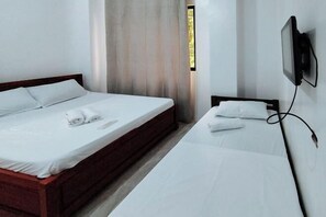 A room with a large bed, a smaller bed, a TV mounted on the wall, and a window with curtains. - RedDoorz @ Elton Guesthouse (Numancia)