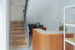 A staircase leading to a landing with a wooden reception desk and a potted plant. - RedDoorz @ Elton Guesthouse (Numancia)