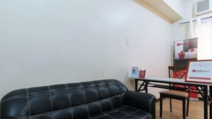 Un sofá de cuero negro en una habitación con una mesa y sillas de madera, un letrero de RedDoor y el logotipo de RedDoor en la pared.