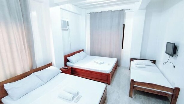 Habitación de hotel con dos camas, televisor y ventana con cortinas.