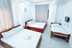 A hotel room with two beds, a TV, and a window with curtains. - RedDoorz @ Elton Guesthouse (Numancia)