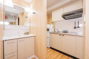 A compact kitchen with a microwave, coffee maker, and a black range hood. - skytree Family Hotel (Tokyo)