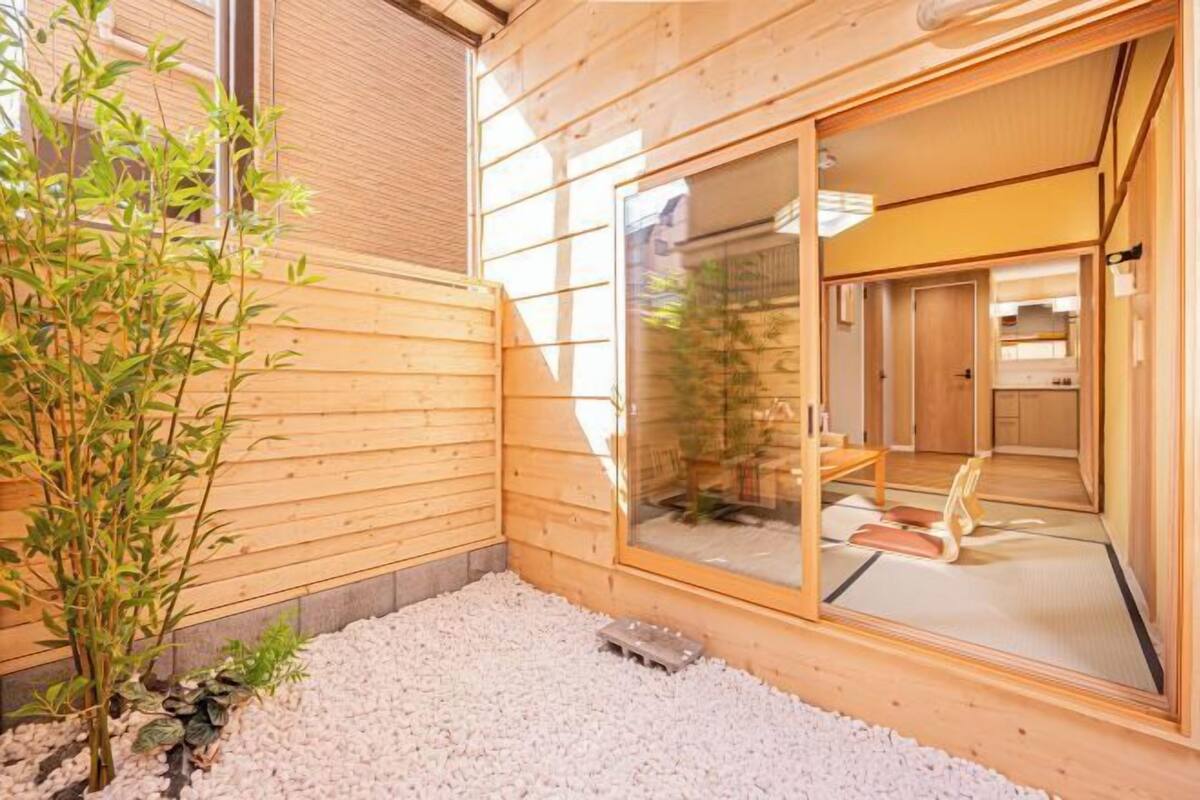 A wooden exterior with a sliding glass door leading to a room with tatami mats and a traditional Japanese interior.
