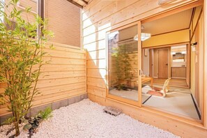 Eine Holzwand mit einer Schiebetür zu einem Raum mit Tatami-Matten und traditionellem japanischen Interieur.